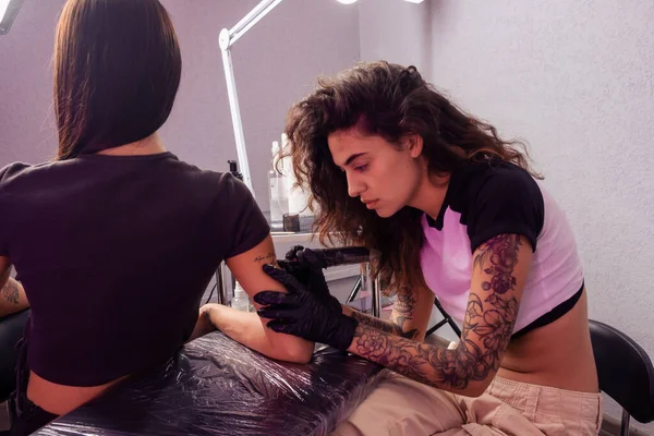タトゥーマシンを使用して クライアントの腕にパーソナライズされたレタリングデザインを巧みに作成することに焦点を当てたプロの女性タトゥー — ストック写真