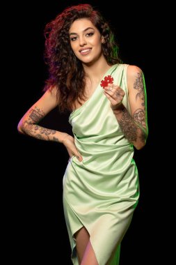 Kumarhanede kazandıktan sonra elinde iki kırmızı bahis fişi tutan neşeli, genç bir esmer. Yetişkinler için eğlence ve kumar bağımlılığı kavramı