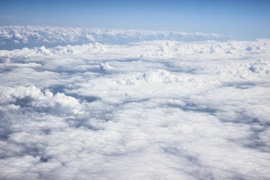 Mavi gökyüzü ve güneş ışığı olan bir uçağın görüntüsünden ağır beyaz gri bulutlar bulutların üzerinde uçuyor.