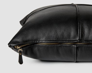 Pürüzsüz, hakiki siyah deriden yapılmış el yapımı kanepe yastığı ve beyaz arka planda altın rengi fermuar. İç tasarım için lüks aksanlar