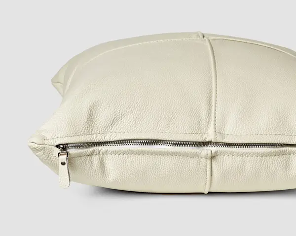 Rahat etmek için metal fermuarlı, pürüzsüz, beyaz, hakiki deri parçalardan yapılmış el yapımı kanepe yastığının yakın görüntüsü. İç tasarım için sanatsal aksesuar