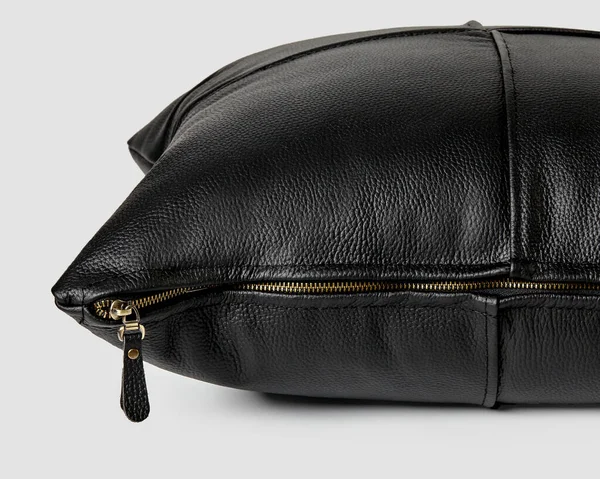 Pürüzsüz, hakiki siyah deriden yapılmış el yapımı kanepe yastığı ve beyaz arka planda altın rengi fermuar. İç tasarım için lüks aksanlar