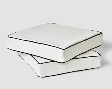 İki zarif, beyaz deri döşeme yastığı, açık gri arka planda siyah boruyla detaylandırılmış. Şık iç tasarım için el yapımı ögeler