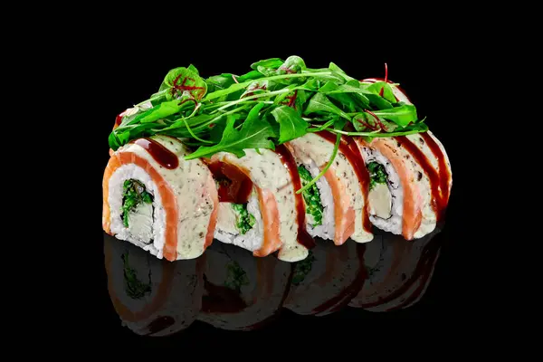 Delicious sushi rolls filled with cream cheese and hiyashi wakame wrapped in salmon fillet, topped with peanut sauce and savory unagi sauce, served with fresh greens on black reflected surface