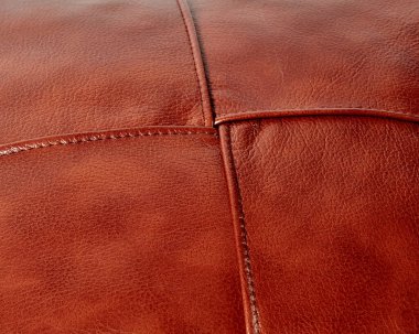 Background of stitched square patches of copper-coloured genuine leather. Handcrafted furniture upholstery. Textured pattern