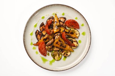 Izgara kabak dilimleri, patlıcan, dolmalık biber, domates ve mantar serpiştirilmiş canlı yeşil bitki sosu benekli tabakta servis edilir, üst manzara. Sağlıklı ve lezzetli abur cuburlar için vejetaryen yemeği