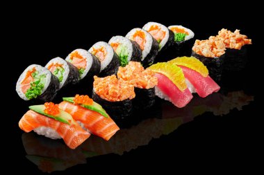 Göz alıcı bir futomaki, gunkan maki ve nigiri sushi seti havyar, salatalık ve portakal özüyle süslenmiş somon ve ton balığı yansıtıcı siyah yüzeyde sunulmaktadır. Japon füzyon mutfağı.