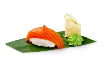 Yumurtalı lezzetli somon nigiri suşi, turşulu zencefil ve wasabi beyaz arka planda izole edilmiş yeşil bambu yaprağında servis edilir. Geleneksel Japon mutfağı. Suşi bar menüsü kavramı
