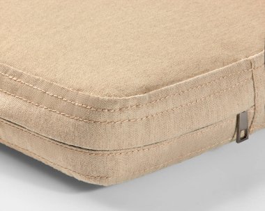 Bej renkli bir kumaş kaplama köşesine yakın plan, düzgün dikişler ve kısmen görünür bir fermuar.