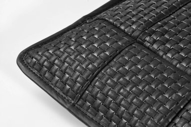 Örgü dokusunu ve cep detaylarını vurgulayan siyah deri bir çantanın yakın çekimi