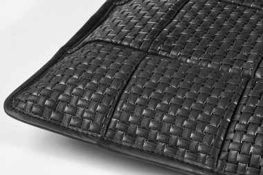 İç içe geçmiş siyah deri şeritlerin yakın çekimleri dokulu bir yüzey oluşturuyor, işçiliği ve malzemeyi vurguluyor.