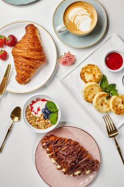 Lezzetli bir kahvaltı, kruvasanlar, krepler, granola, kapuçino ve böğürtlenlerle nefis bir aşçılık sahnesi yaratıyor.