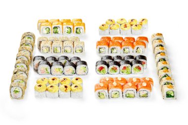 Çeşitli malzemelerle taze suşi ruloları temiz beyaz bir yüzey üzerinde renkli ve iştah açıcı bir düzenleme yaratıyor.