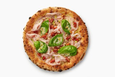 Gurme pizzanın üstünde mortadella, şam fıstığı, güneşte kurutulmuş domates, fesleğen ve parmesan peyniri var.