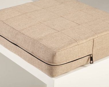 Görünür bir fermuarla bej kumaş yastığının yakın çekimi, kumaşın işçiliğini ve dokusunu vurguluyor.