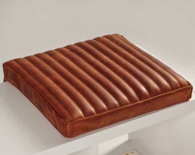 Kahverengi deri koltuk minderiyle dikey kaburgalar beyaz bir bankın üzerine bir tutam kırsal cazibe ekler, rahat ve davetkar bir yer yaratır.