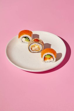 Çeşitli dolguları olan suşi parçaları seramik bir tabağa güzelce yerleştirilmiş, baştan çıkarıcı bir mutfak sahnesi yaratıyor.