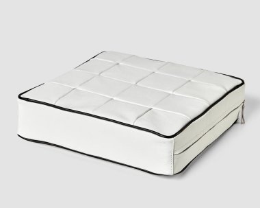 Stüdyo resmi, beyaz beyaz arka planda siyah boruları olan beyaz deri bir pouf.