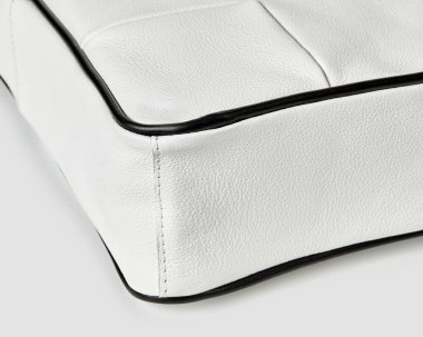 Siyah borularla kaplı beyaz deri çanta, işçiliği ve dikişleri vurguluyor.