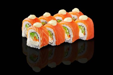 Somon, avokado, krem peynir ve masago ya da tobiko havyarlı lezzetli Philadelphia uramaki suşisi siyah arkaplanı yansıtıyor.