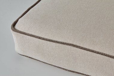 Kahverengi kenarlı bej kumaş yastığın yakın çekimi, dokuyu ve dokuyu gösteriyor.