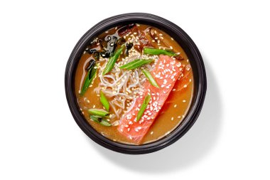 Somon balıklı Miso çorbası, cam şehriye, wakame yosunu, mantar, taze soğan ve susam tohumları siyah kasede servis edilir.