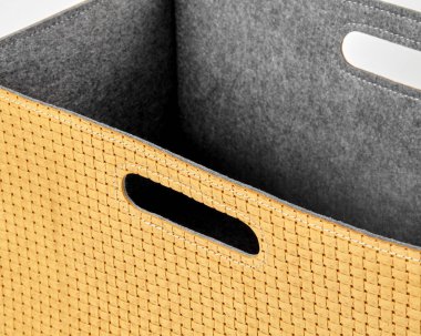 Gri keçe astarlı ve kullanışlı tutacakları olan boş sarı dokuma bir depo kutusuna yakın plan.