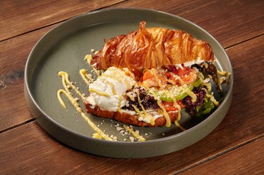 Karides, avokado ve salata ile dolu taze yapılmış kruvasan sandviçi, şık bir tabakta servis edilir, gurme kahvaltısı ya da brunch için mükemmeldir.