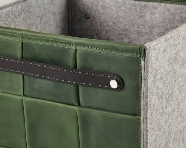 Gri keçeli astarı ve dayanıklı deri sapı olan zarif, yeşil deri bir depo kutusunun yakın çekimi.