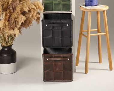 Zarif deri kutuları, ahşap taburesi ve minimalist bir ortamda otları olan modern ev organizasyonu.