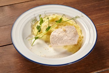 Kurutulmuş tavuk göğsü kremalı patates püresi, taze bezelye filizi ve bir tutam sos ile servis edilerek sofistike bir aşçılık deneyimi yaratıldı.