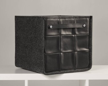 Siyah deri ve gri keçeyi birleştiren şık bir depolama kutusu, eşyaları düzenlemek için ideal.