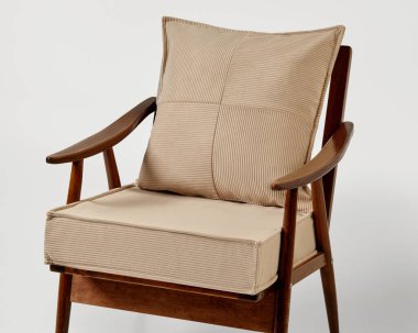 Ahşap çerçeveli modern koltuk ve bej kadife döşeme ile uyumlu yastık ve yastık, rahat ve şık bir oturma düzeni oluşturur