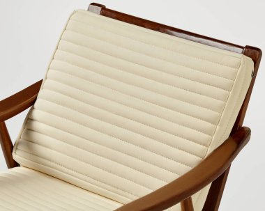 Ahşap sandalye bir krem sergiliyor, yatay çizgili döşeme, rahatlık ve modern tasarım estetiği vurguluyor.