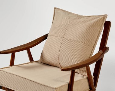 Bej renkli kadife döşemeli modern koltuk ve uyumlu bir yastık. Minimalist ve şık bir tasarım sergiliyor.