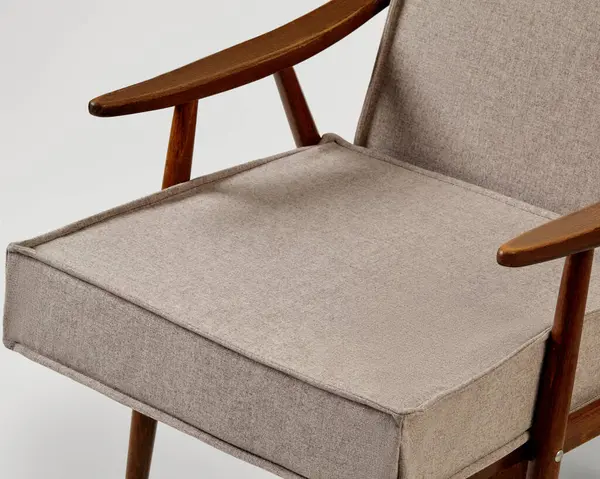 Gri yastıkları ve ahşap yapısı olan rahat modern koltuk, şık bir oturma odasında dinlenmek için mükemmel.