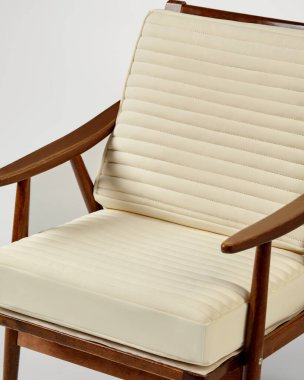 Tahta koltuk, krem rengi yastıklı. Rahat ve stil karışımı bir şey sunuyor. Herhangi bir iç mekâna zerafet katmak için mükemmel.