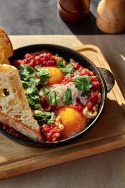 Tost ekmeği, otlar ve baharatlarla nefis shakshuka dökme demir bir tavada servis edilir, sıcak güneş ışığının tadını çıkarırlar.