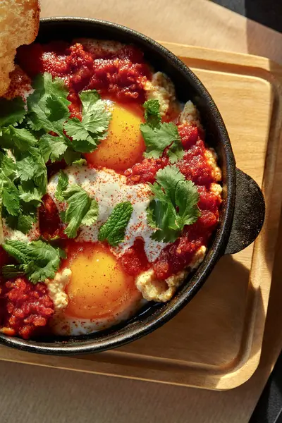 Shakshuka, Orta Doğu ve Kuzey Afrika yemekleri, lezzetli domates sosunda haşlanmış yumurtalar, taze otlarla süslenmiş.