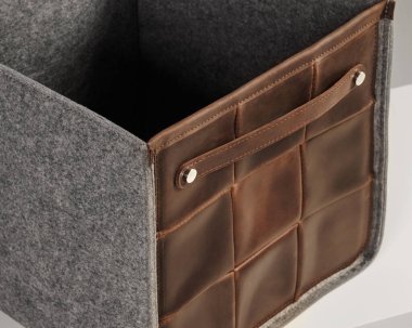 Kahverengi deri ve gri keçeden yapılmış şık boş bir depo kutusu, kullanışlı bir sapı var.