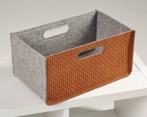 Şık dokuma deri ve beyaz bir rafta duran bir depolama sepeti, düzenlemek ve azaltmak için ideal