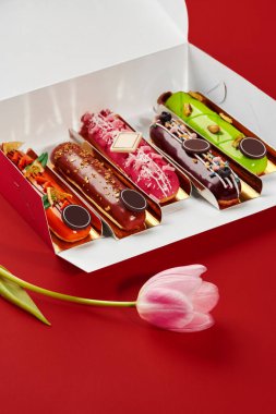 Kırmızı arka planda pembe lale olan açık kutuda renkli ekler. özel bir olayı kutluyorlar.