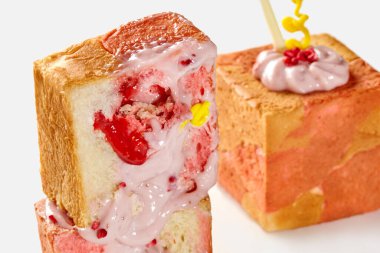 İki dilim çilek aromalı, pembe kremalı ve çilekli ekmek görsel olarak çekici bir tatlı oluşturur.