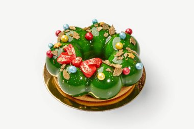 Renkli süslemeler, yıldızlar ve kırmızı bir fiyonk ile süslenmiş yeşil jöleli Noel pastası.