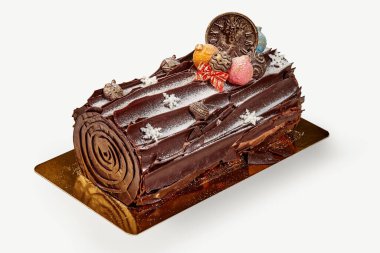 Geleneksel noel çikolatalı pasta yenilebilir süslemeler, krema şekeri ve şenlikli süslemeler ile süslenmiş, altın tepside dinleniyor.