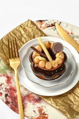 Çikolata ve karamel turtası beyaz bir tabakta altın çatal bıçakla, tadını çıkarmaya hazır.