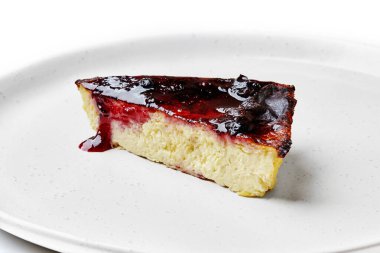 Beyaz bir tabakta servis edilen bol yaban mersini soslu kremalı New York usulü peynirli kek.