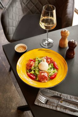 Beyaz şarapla servis edilen burrata, prosciutto ve pesto soslu lezzetli gurme makarna.