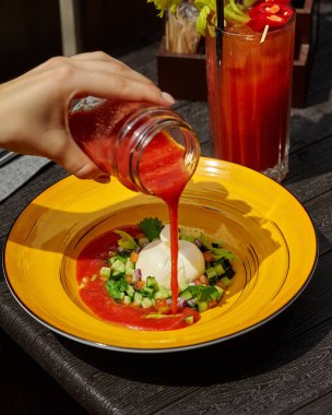 Burrata peyniri ve sebze salatasının üzerine domates çorbası dökülüyor.