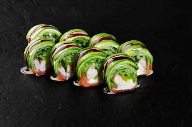 Lezzetli yeşil ejderha suşi dürümleri çok güzel sunuluyor, avokado, somon ve krem peynirle birlikte unagi sosu serpiştirilmiş.